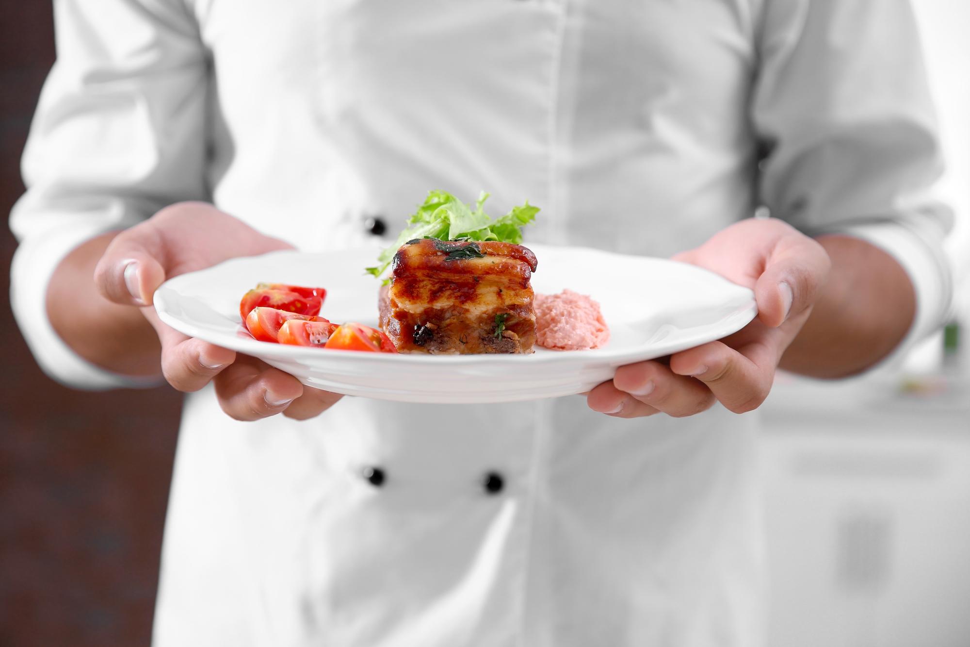 Chef arranging a modern plated dish in a small kitchen